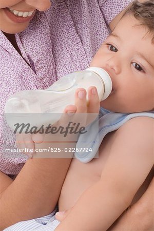 Gros plan d'une femme adulte mid nourrir son fils avec un biberon et souriant
