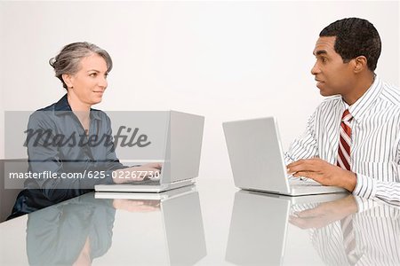Geschäftsfrau und Geschäftsmann auf Laptops in einem Büro arbeiten