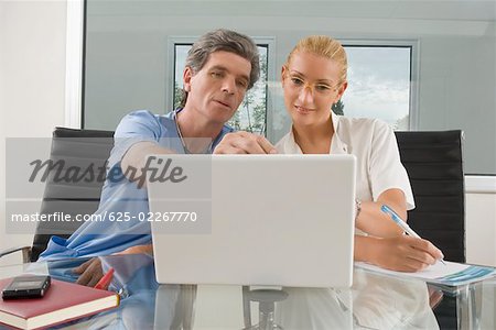 Femme médecin et chirurgien homme assis devant un ordinateur portable