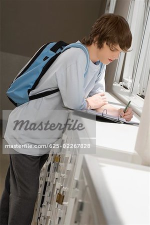 Side profile of a high school student writing in a ring binder