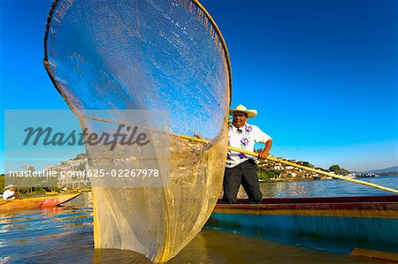 Fischer mit Schmetterling Angeln net in einem See, Insel Janitzio, Lake Patzcuaro, Patzcuaro, Bundesstaat Michoacan, Mexiko