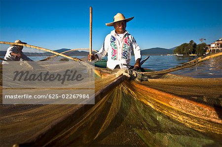 Fischer mit Schmetterling Angeln net in einem See, Insel Janitzio, Lake Patzcuaro, Patzcuaro, Bundesstaat Michoacan, Mexiko