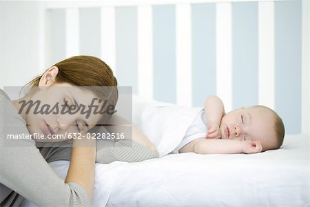 Mother resting head beside sleeping infant, eyes closed