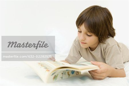 Boy lying on stomach, reading book