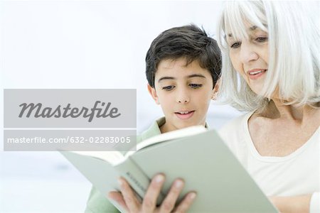 Grandmother and grandson reading book together