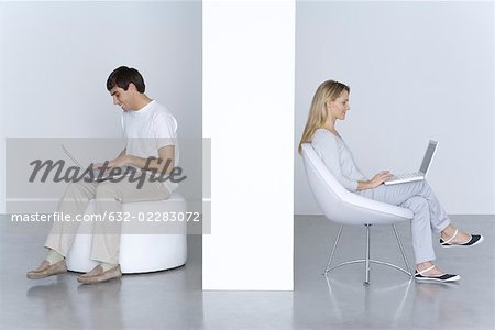 Mann und Frau sitzen separat, mit einem Laptopcomputer, Lächeln