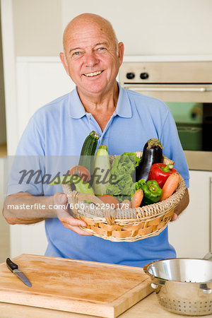 Portrait of Man in Kitchen Holding Basket of Vegetables