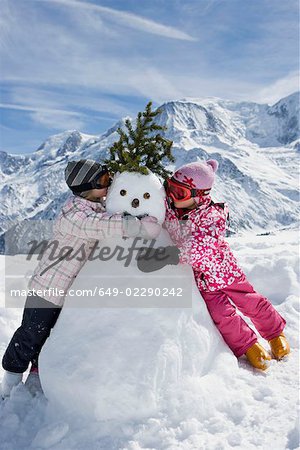 Zwei Mädchen mit einem Schneemann