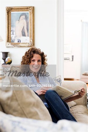 Woman reading a book sitting on a couch