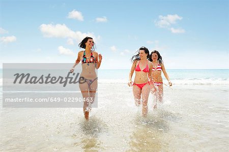 Trois filles en cours d'exécution dans les vagues