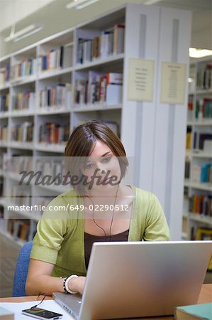 Jeune femme travaillant sur ordinateur portable dans la bibliothèque