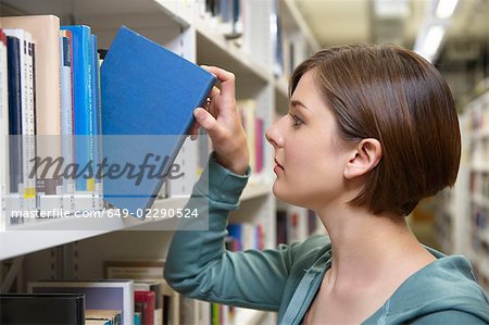 Jeune femme avec le livre de la bibliothèque
