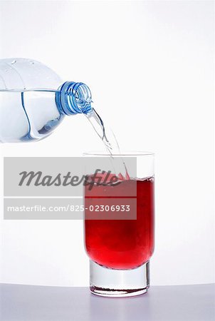 Pouring water into a glass of grenadine syrup