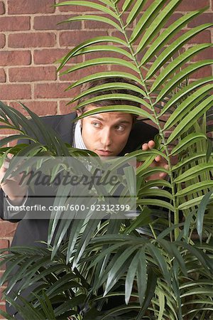 Man Peeking From Behind a Plant