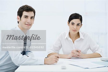 Professionals sitting with documents, smiling at camera