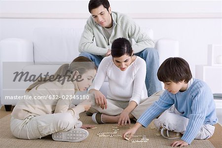 Familie verbringen Zeit zusammen, Mutter und Kinder spielen Dominosteine Vater beobachten