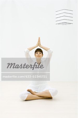 Woman sitting in tree pose on the floor, looking up