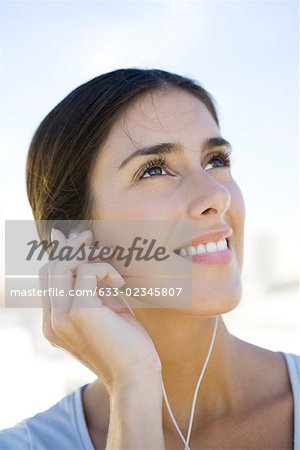 Woman looking up, listening to earphones