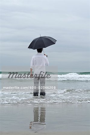 Homme tenant un parasol sur la plage