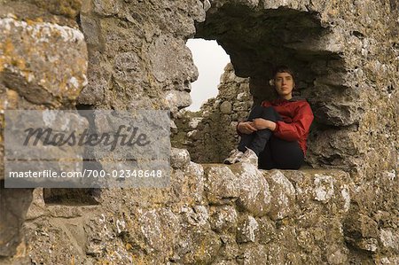 Femme assise dans la fenêtre du monastère de Kilmacduagh, Kilmacduagh, comté de Galway, Irlande