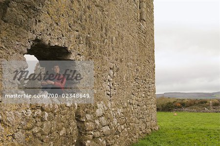 Femme assise dans la fenêtre du monastère de Kilmacduagh, Kilmacduagh, comté de Galway, Irlande