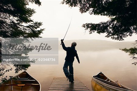 Boy Fishing Off Dock Early in the Morning, Algonquin Park, Ontario, Canada