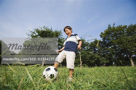 Boy playing with football in park