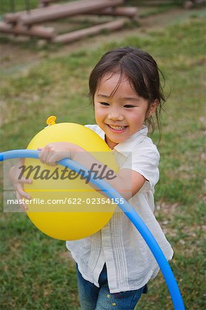 Lächelnd mädchen spielen mit Ballon im park