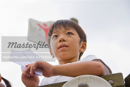 Boy holding paper aeroplane
