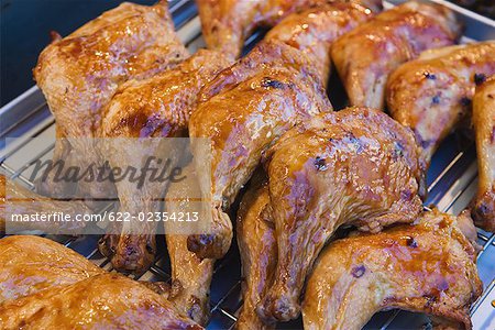 Barbecued chicken legs being cooked on grill