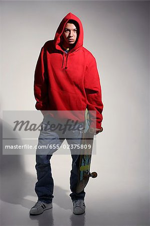 young man wearing red hooded sweatshirt holding skateboard