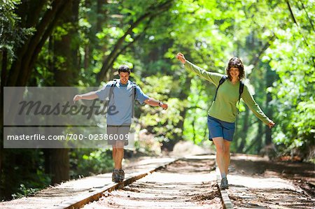 Paar balancieren auf Eisenbahn-Tracks in Wald, Santa Cruz, Kalifornien, USA