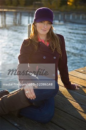 Frau sitzt auf Dock am See