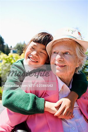 Mädchen umarmt von ihrer Großmutter in einem Garten