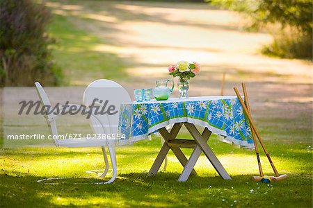 Two chairs with a table and croquet mallets in a garden