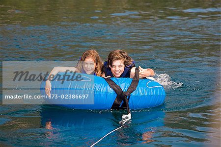 Boy on an inflatable ring with his sister in a lake