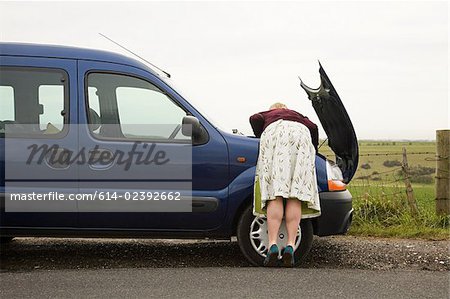 Woman looking under car bonnet