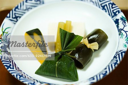 Assortiment d'aliments japonais sur plaque, courges d'hiver, tofu, légumes marinés et feuille enveloppé de riz