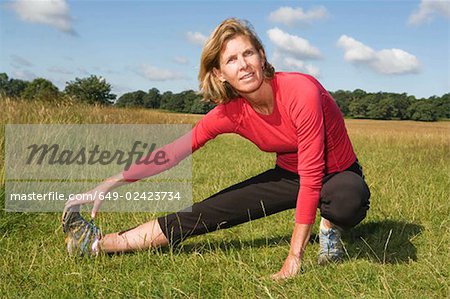 Femme qui s'étend de la jambe dans le champ