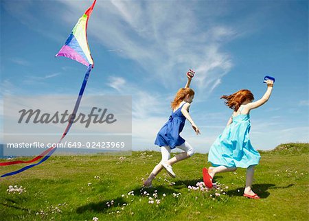 2 young girls running with kites