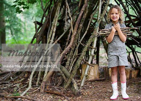 Young girl with pile of twigs in woods