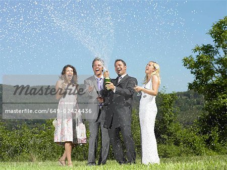 Wedding party popping champagne