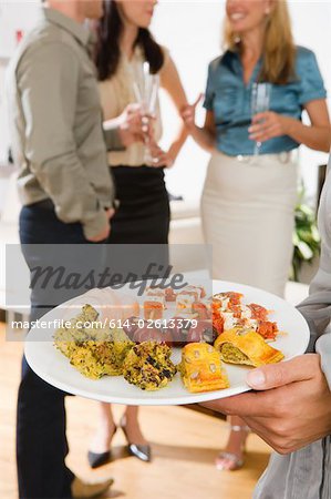 Une femme tenant une assiette de canapés