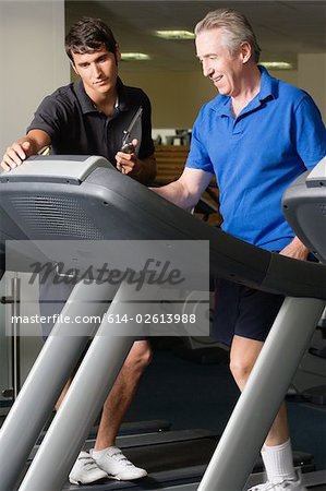 A personal trainer helping a man on a treadmill