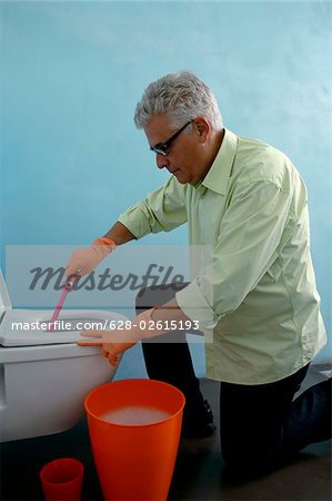 Senior man cleaning the toilet with a brush