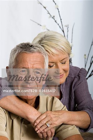 Senior woman embracing man form behind