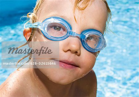 Little boy wearing swimming goggles on a pool, portrait