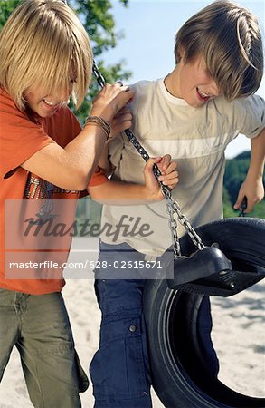 Two Boys pulling the Chains of a Rubber Tire-Swing - Fun - Common Ground - Leisure Time - Playground