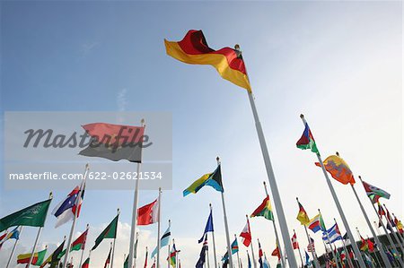 Multinational flags waving against sky