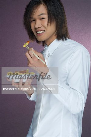 Portrait de l'homme de manger des frites avec des baguettes